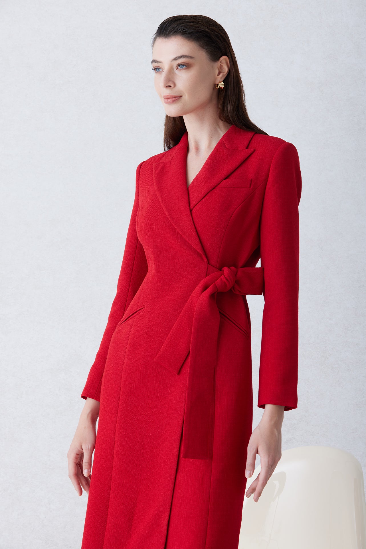 A sophisticated woman walking in London wearing an elegant vibrant red wrap coat dress, featuring a tie-waist belt and notched lapels for a polished executive street style look.