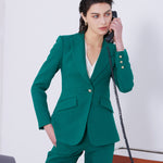 A professional woman wearing a sophisticated emerald green tailored blazer, featuring a slim-fit silhouette, notched lapels, and flap pockets, styled elegantly with a patterned silk scarf for a corporate office look.