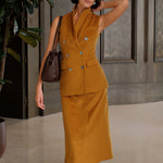 An elegant Asian woman posing in a luxurious camel wool two-piece suit featuring a sleeveless double-breasted longline vest cinched with a wide black belt, paired with a matching midi column skirt and black opera gloves.