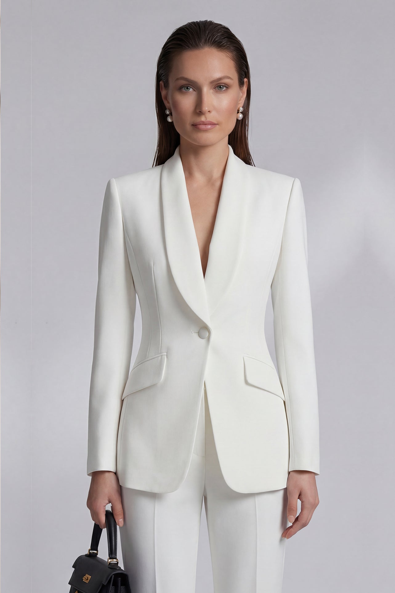 Two professional women showcasing high-end executive business suits: one in a crisp white pant suit with a shawl lapel blazers, and the other in a sophisticated camel skirt suit with a tailored vest, perfect for formal corporate settings.