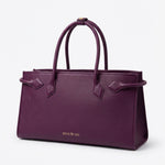 A sophisticated plum purple tote bag crafted from premium pebbled leather, displayed next to a matching shade of luxury lipstick, representing an elegant executive fashion set.