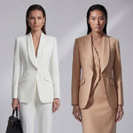 Two professional women showcasing high-end executive business suits: one in a crisp white pant suit with a shawl lapel blazers, and the other in a sophisticated camel skirt suit with a tailored vest, perfect for formal corporate settings.