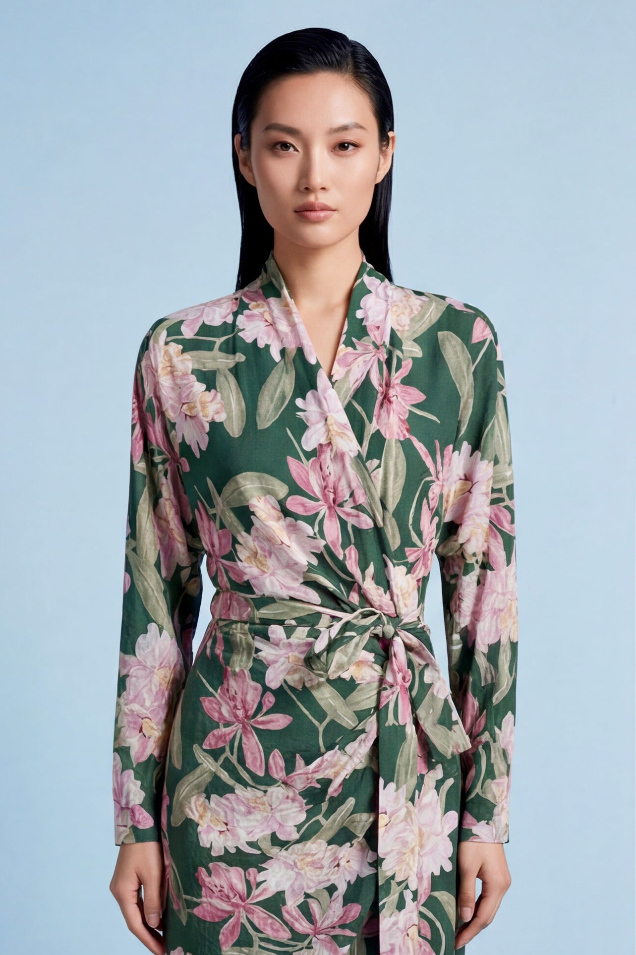 A professional woman wearing a sophisticated dark green wrap dress with a vibrant pink floral print, featuring long sleeves and a slimming waist-tie for an elegant spring look.